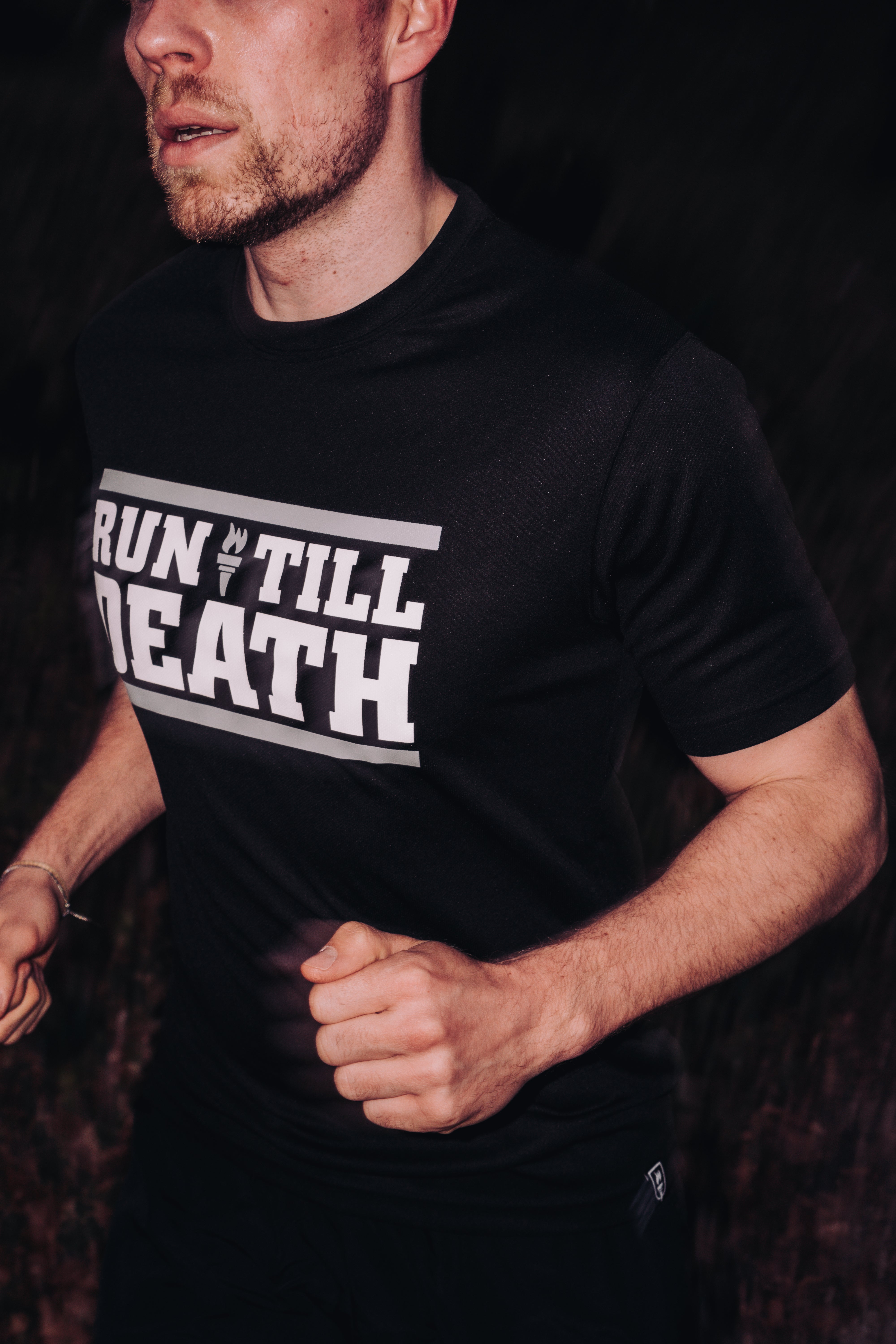 Person wearing a black t-shirt with 'RUN TILL DEATH' text, running outdoors.