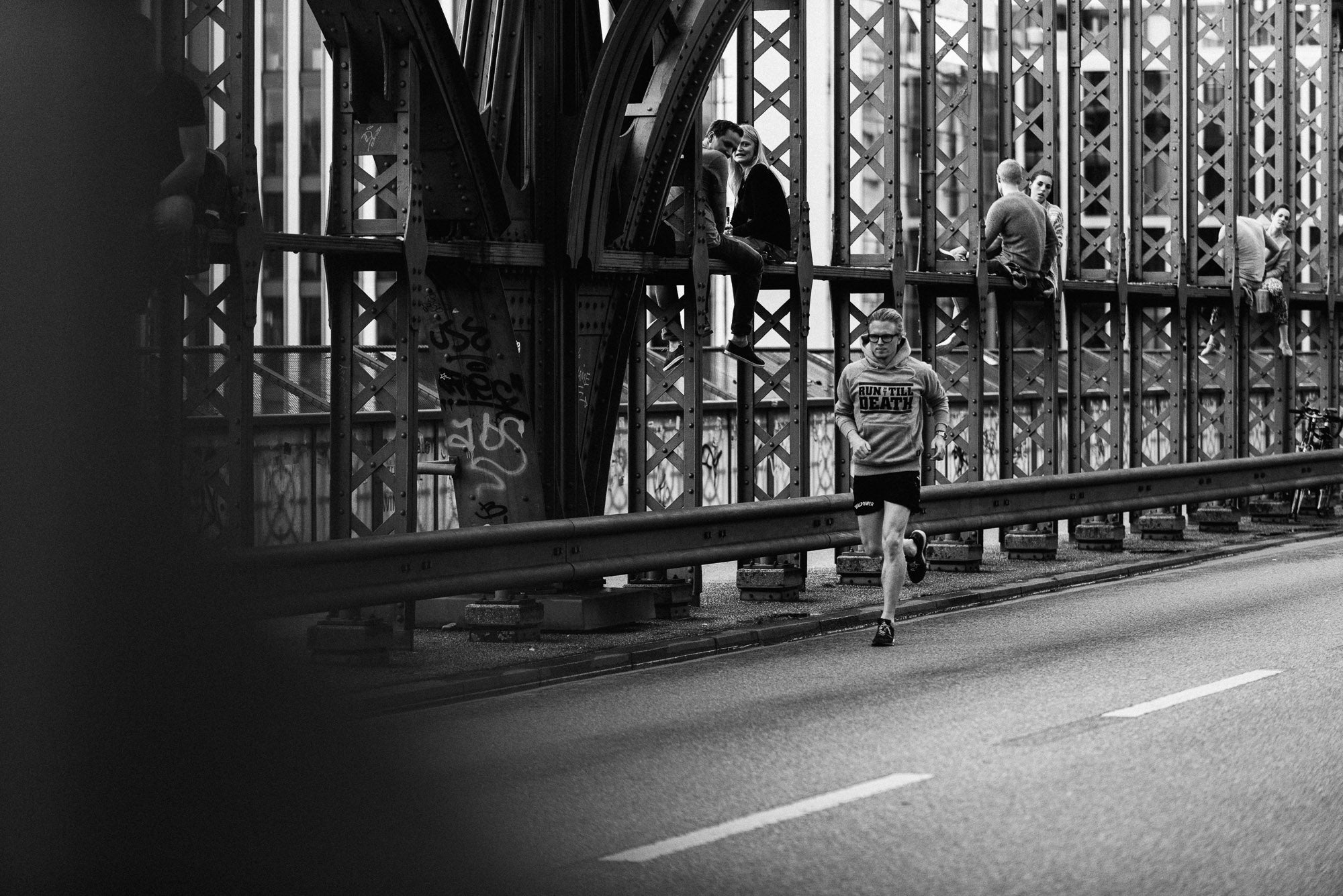 Person running on a road with a metal bridge in the background
