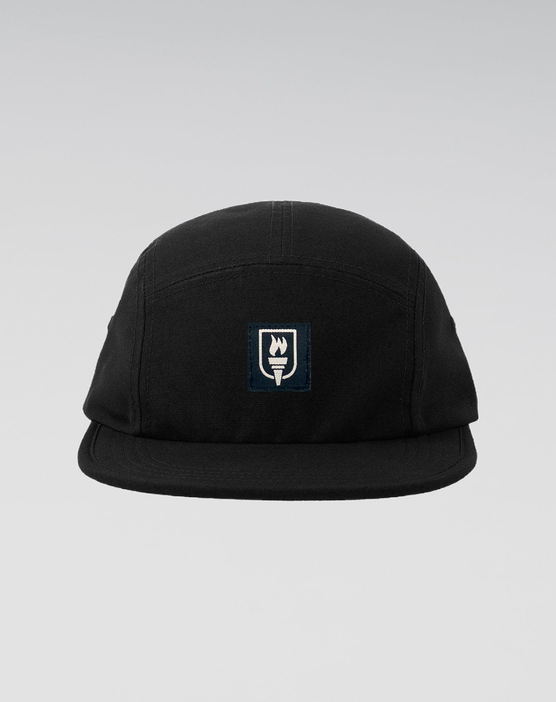 A black five-panel camp cap with a small rectangular embroidered patch on the front featuring a white flame and the word 'SUNRISE' on a dark navy background, set against a light gray gradient studio background.