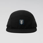 A black five-panel camp cap with a small rectangular embroidered patch on the front featuring a white flame and the word 'SUNRISE' on a dark navy background, set against a light gray gradient studio background.