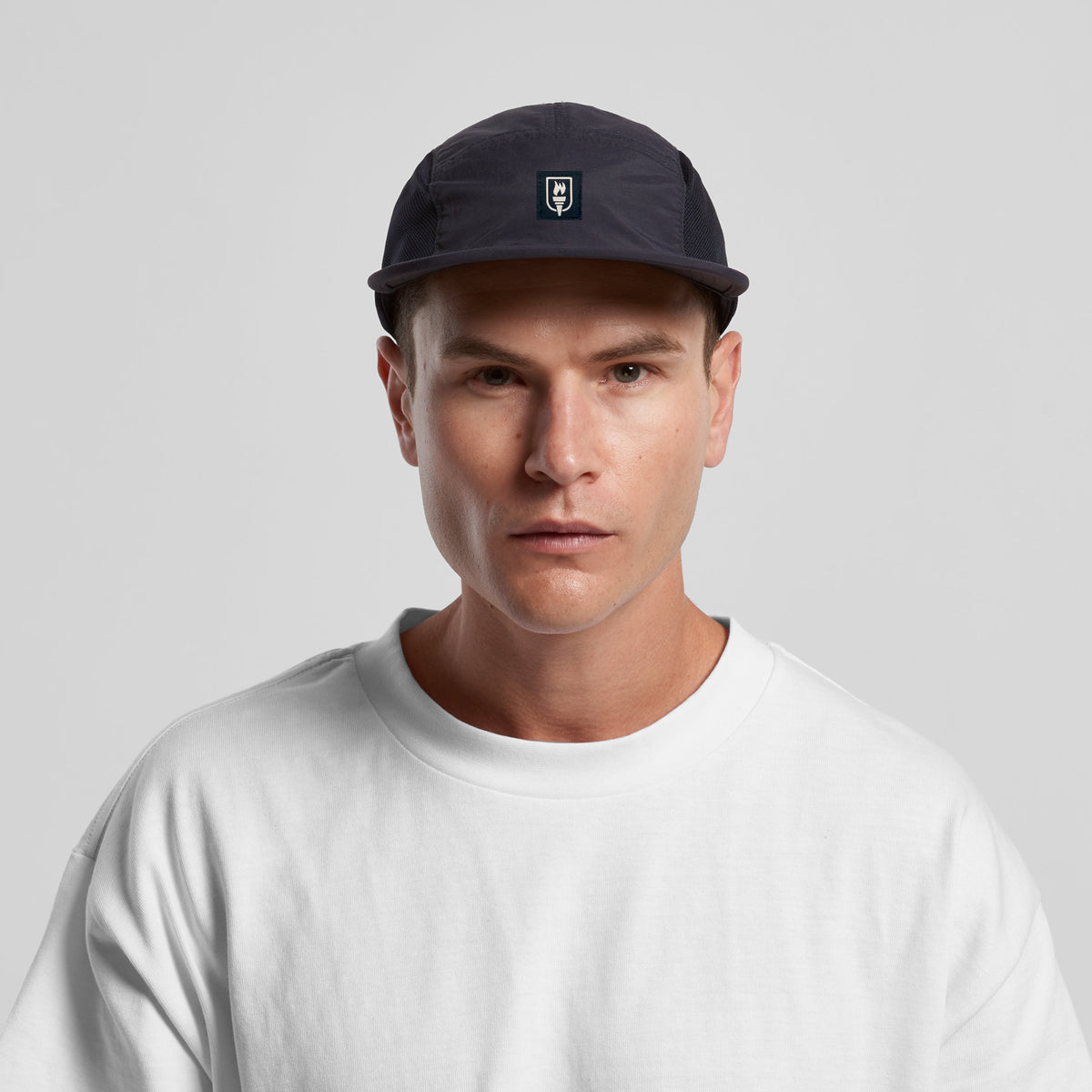 Man wearing a black cap and white shirt against a gray background