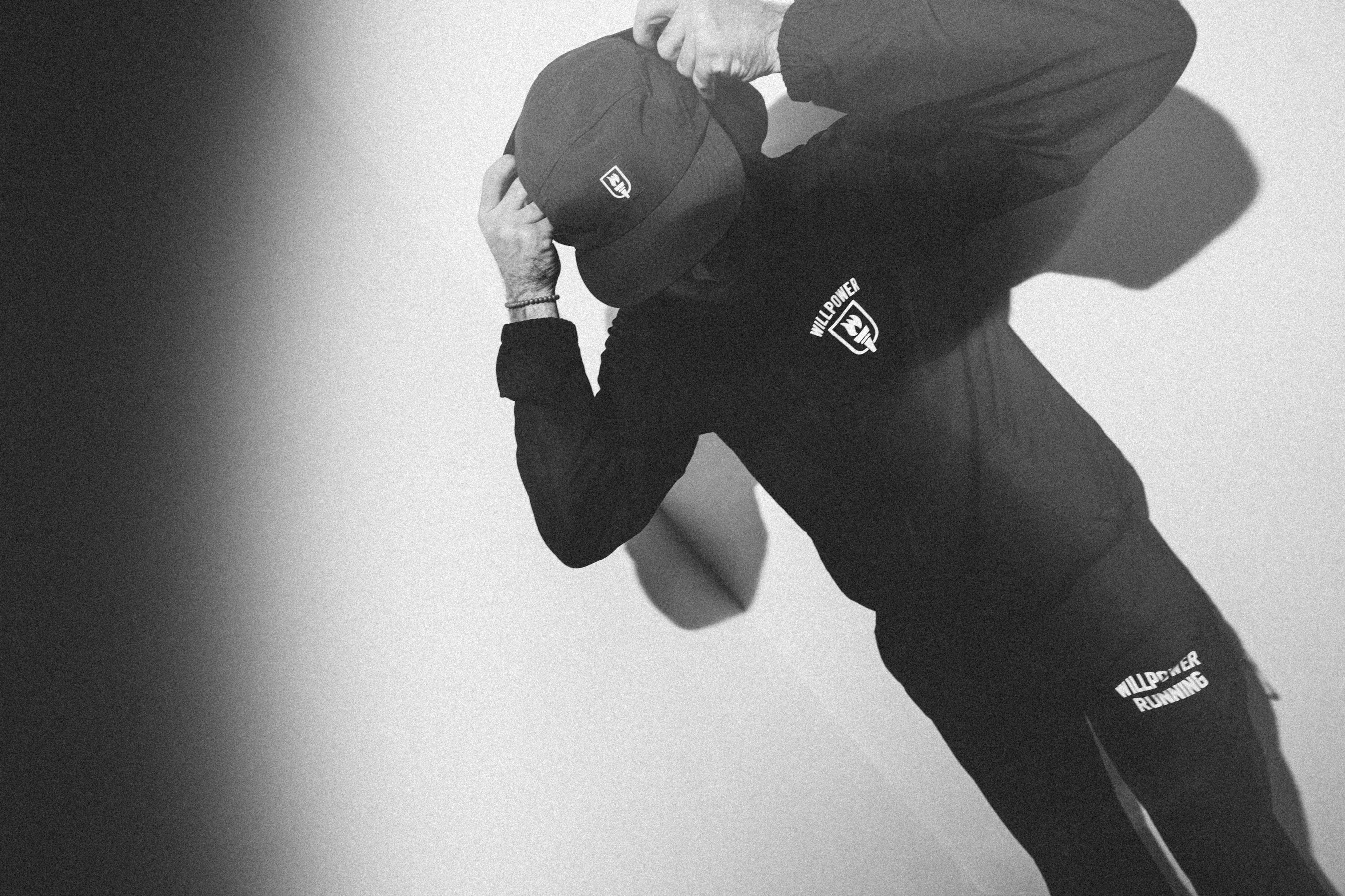 Person wearing a black outfit with logos on a plain background