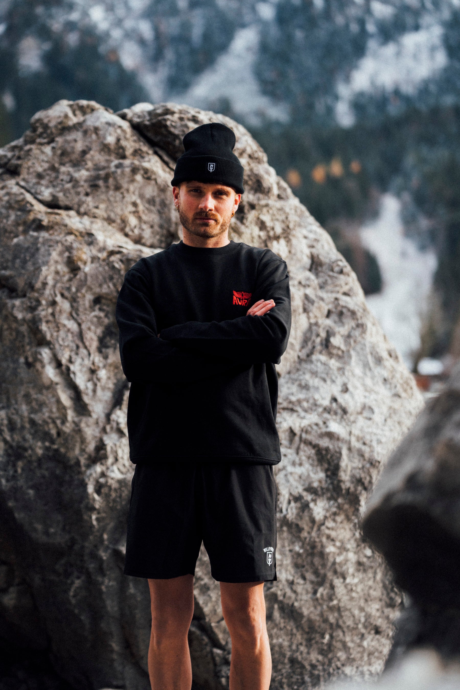 Man in black outfit standing in front of a rocky mountain landscape