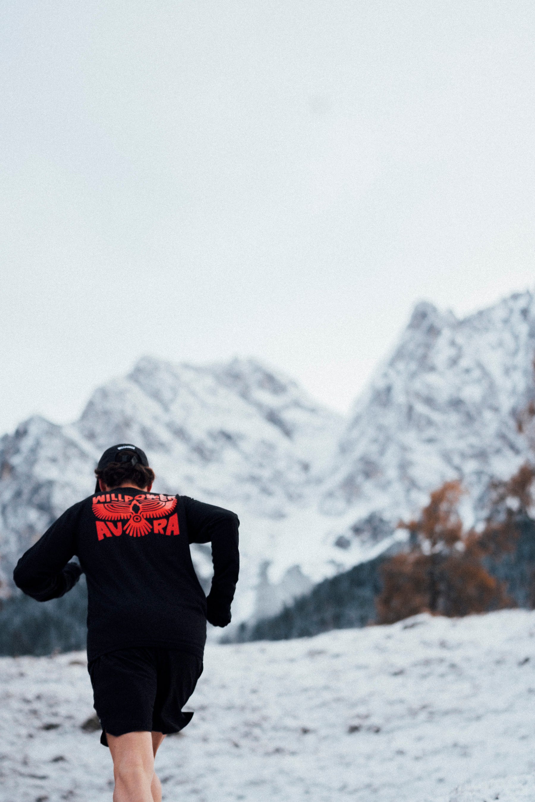 Person running in a snowy landscape with mountains in the background