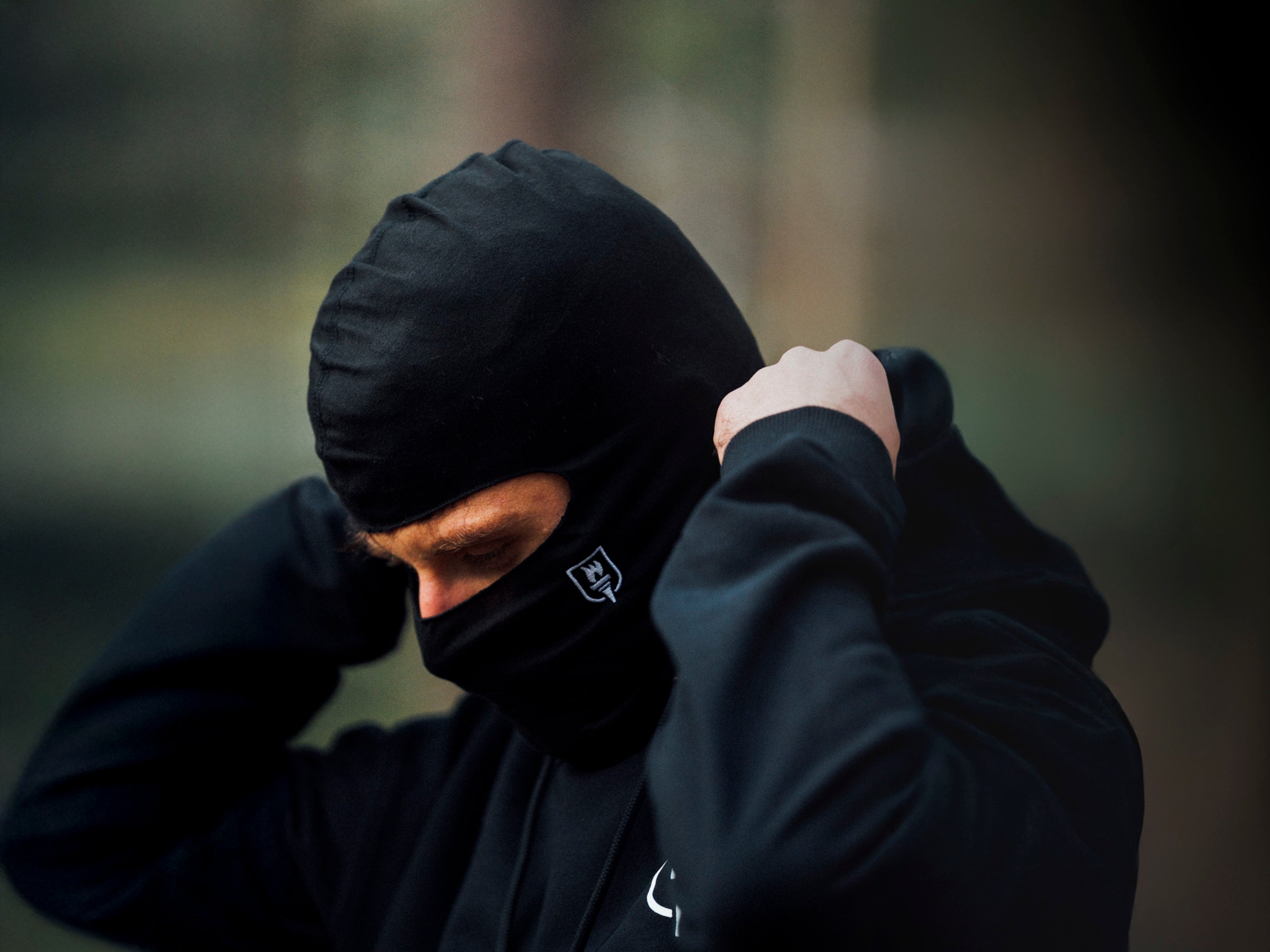 Person wearing a black hooded jacket with a blurred background
