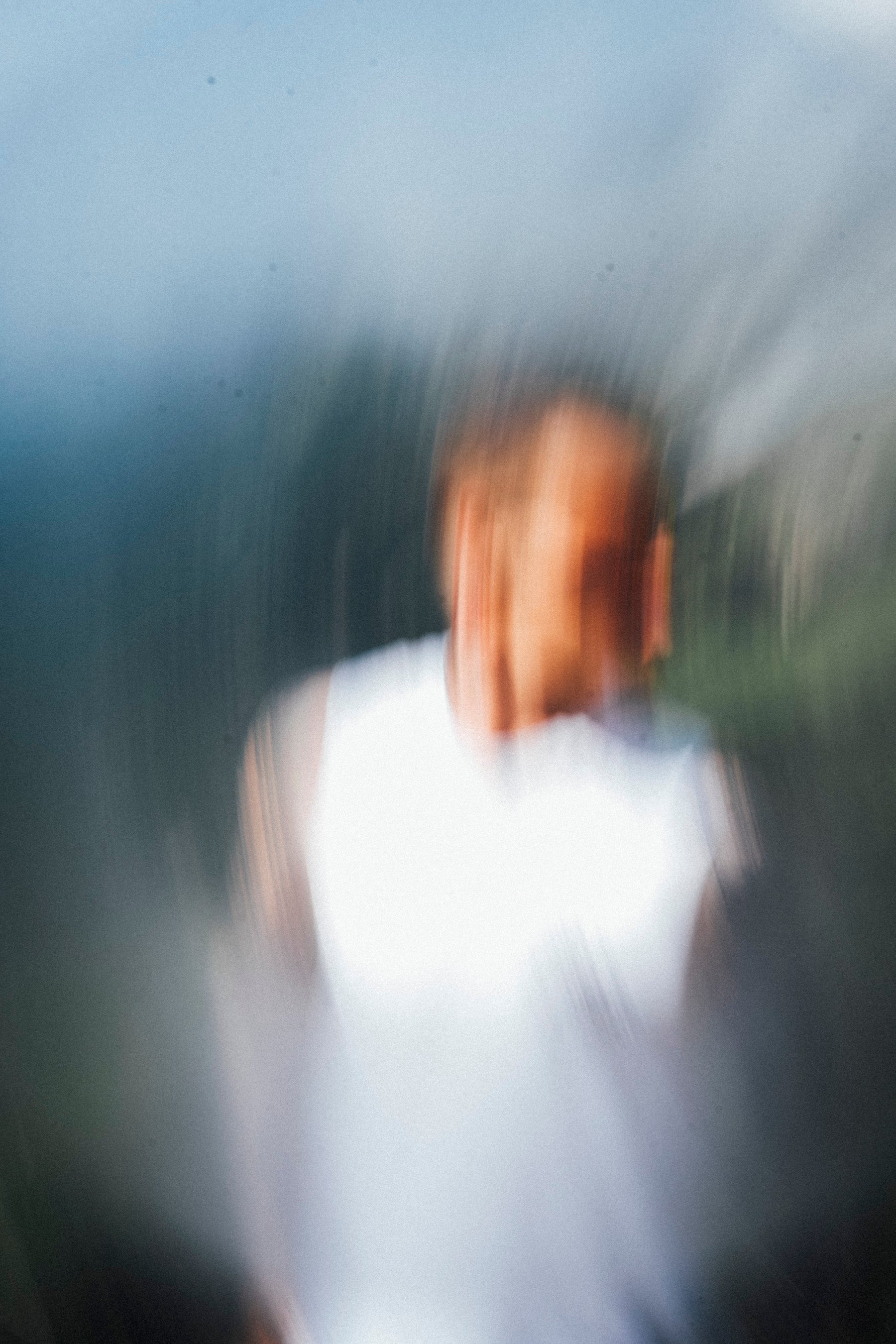 Blurred image of a person with a white shirt and dark hair.